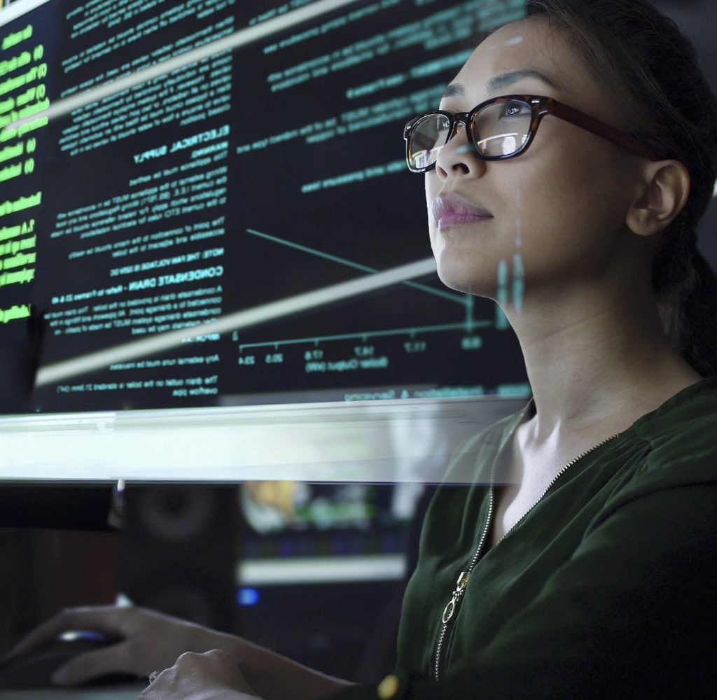Stock photo of a young Asian woman looking at see through data whilst seated in a dark office