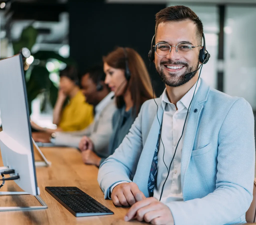 Shot of call center operators working in the office. Call center agent working with his colleagues in modern office. Smiling handsome businessman working in call center.