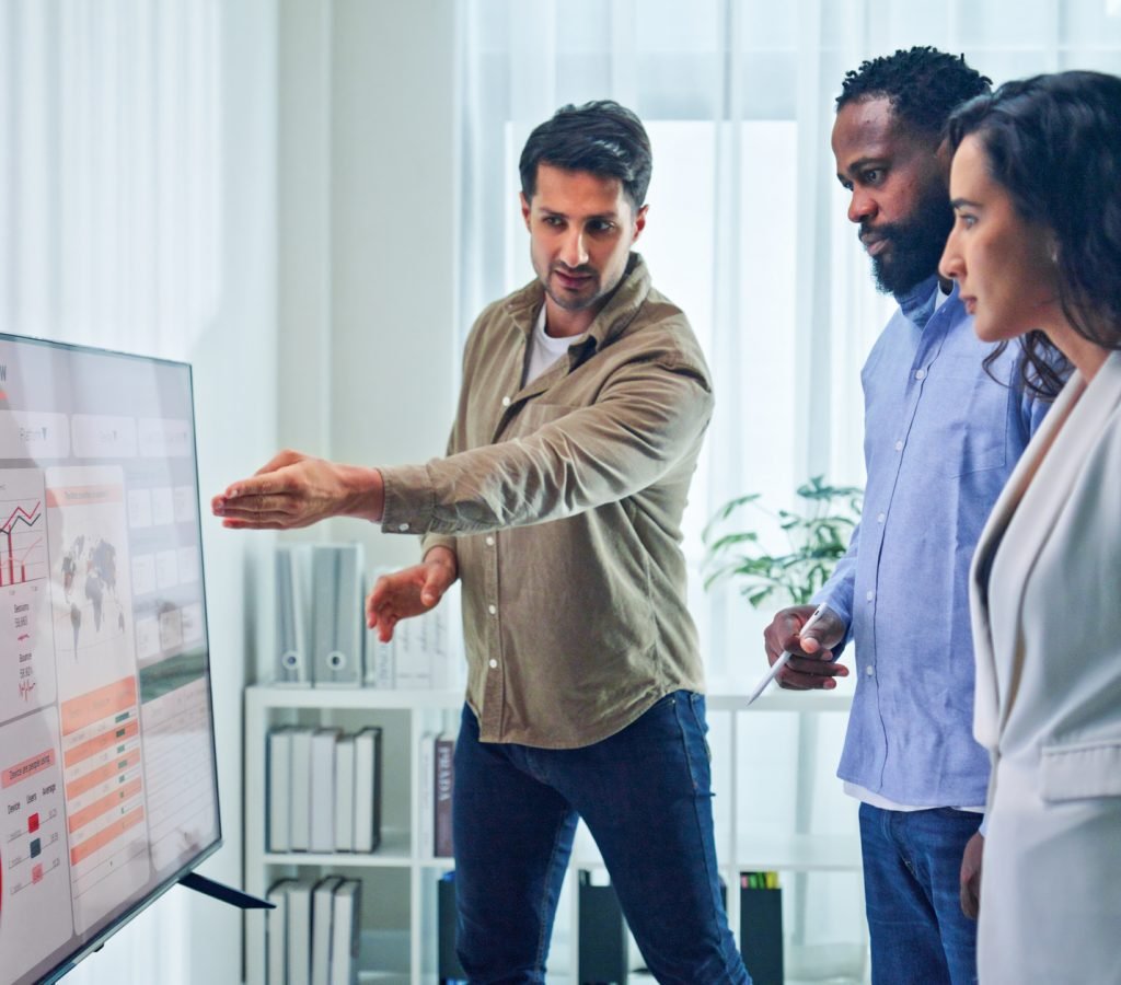 Group of business professionals meeting reviewing global data analytics discussing data analytics during a presentation, discussing strategy and growth standing at office. Finance meeting concept.